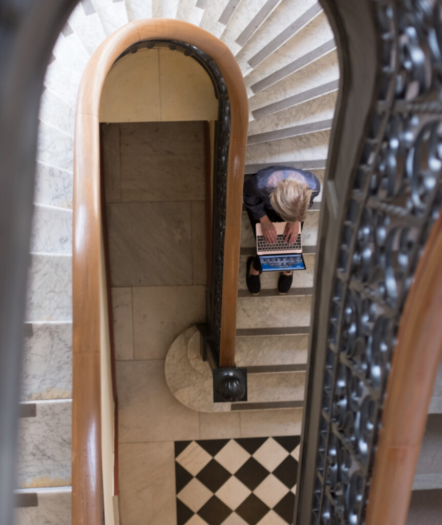 En person sitter i en vacker trappa med laptop i knät